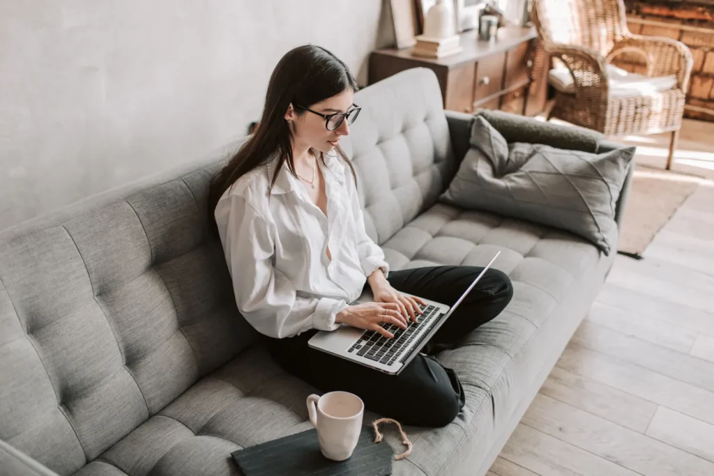 Person using a laptop while seated on a sofa